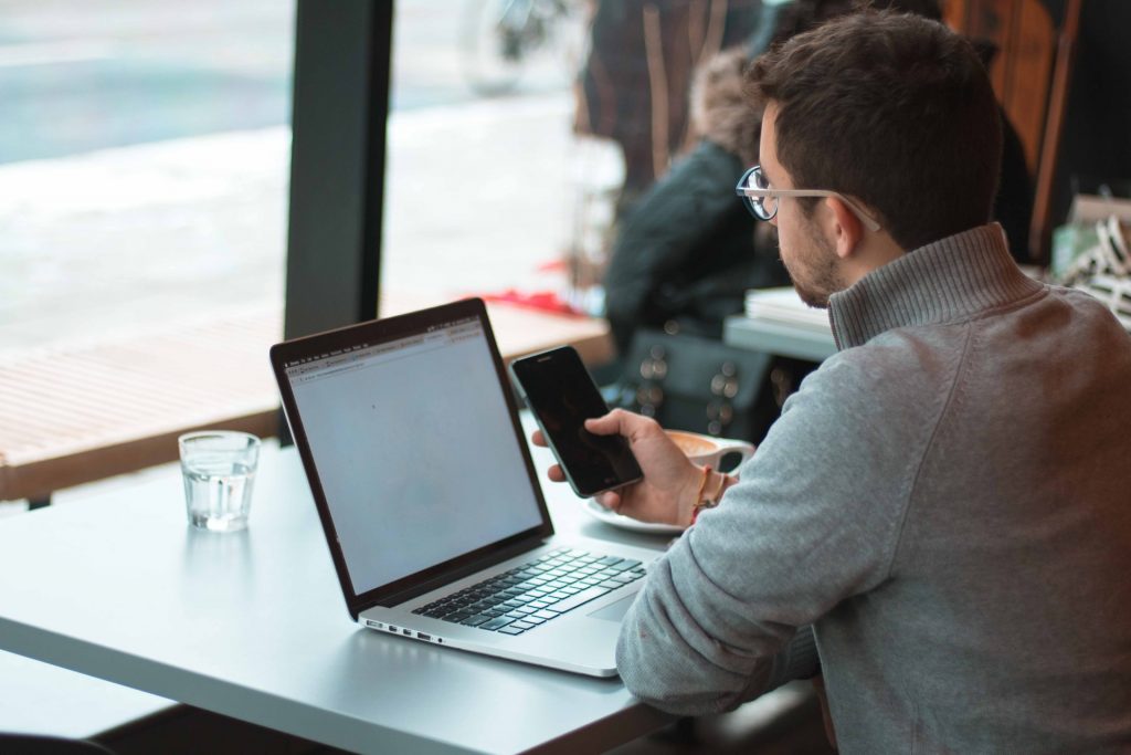 man working on phone and laptop